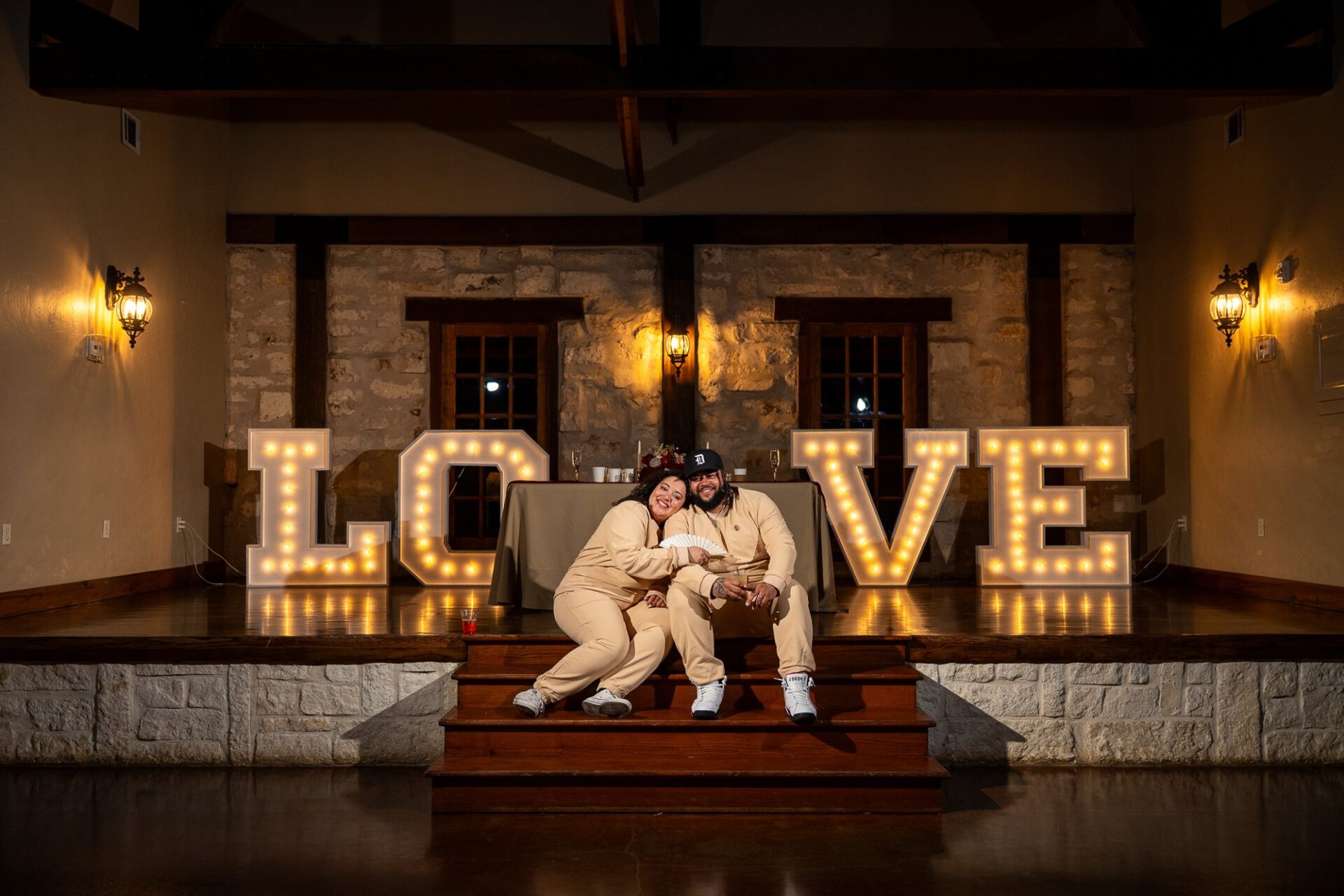 Thomas and Macee seated in front of illuminated LOVE letters