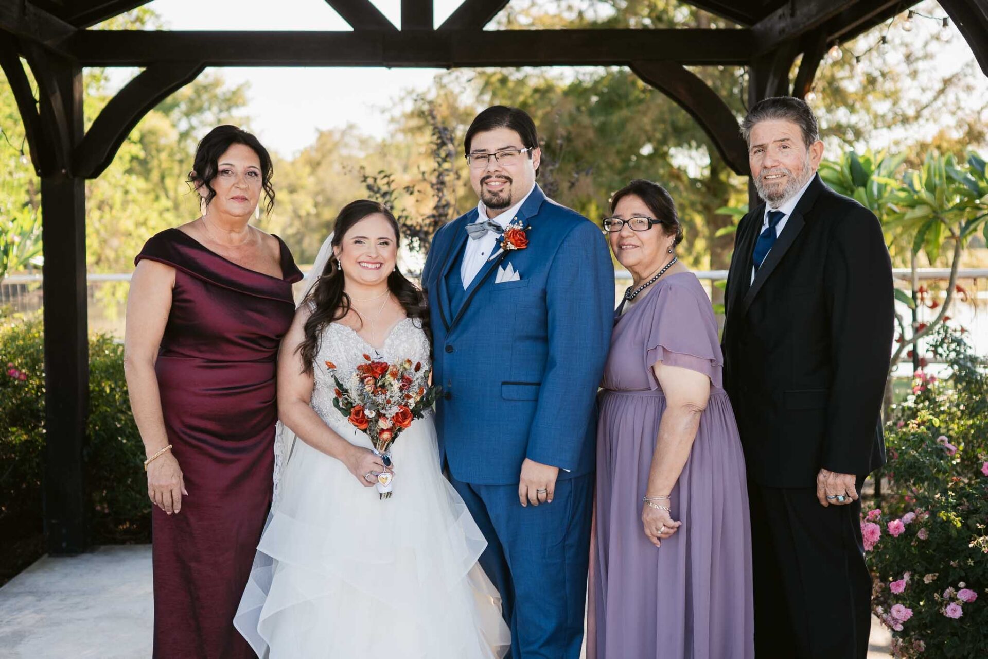 Andreea and Ram pose with family beneath the ranch gazebo beside the pond.
