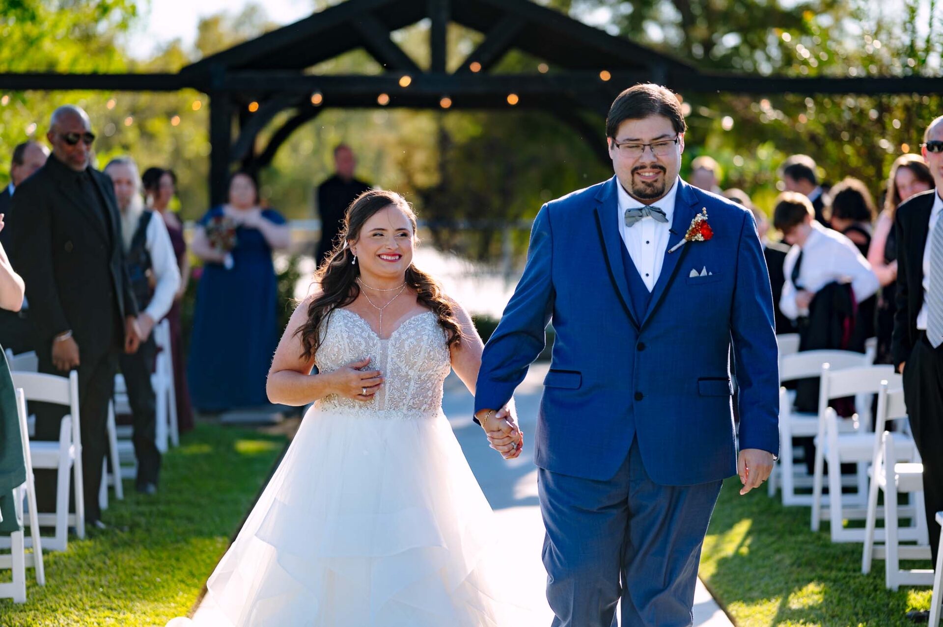 Andreea and Ram walk hand in hand back down the garden ceremony aisle.