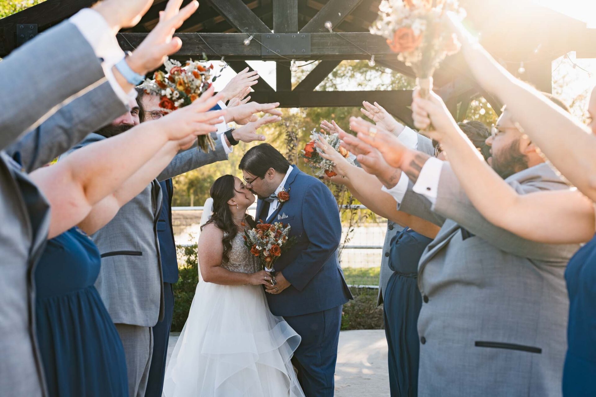 Wedding party raises their hands around Andreea and Ram beneath the gazebo.