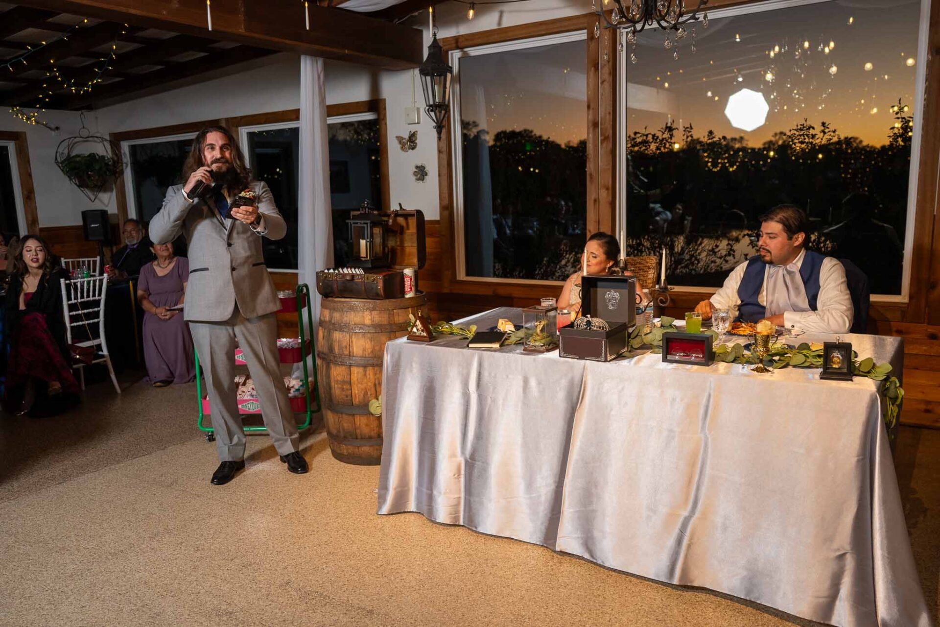 A wedding party member gives a toast as Andreea and Ram listen at the head table.