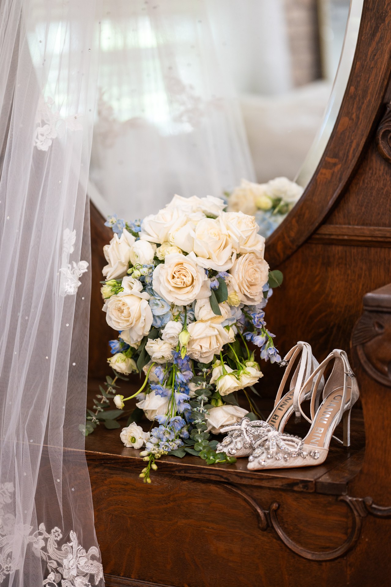 White and pale blue bridal bouquet beside wedding shoes