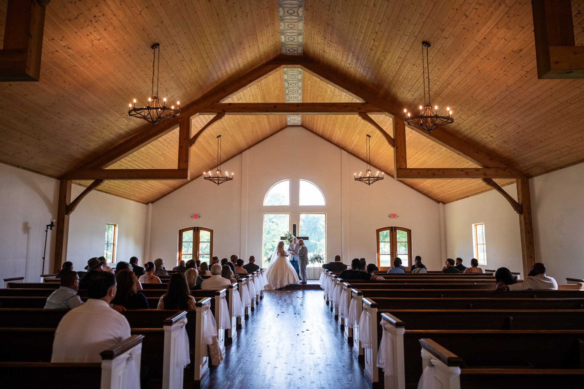 Wide view of guests and the couple beneath the chapel’s timber beams