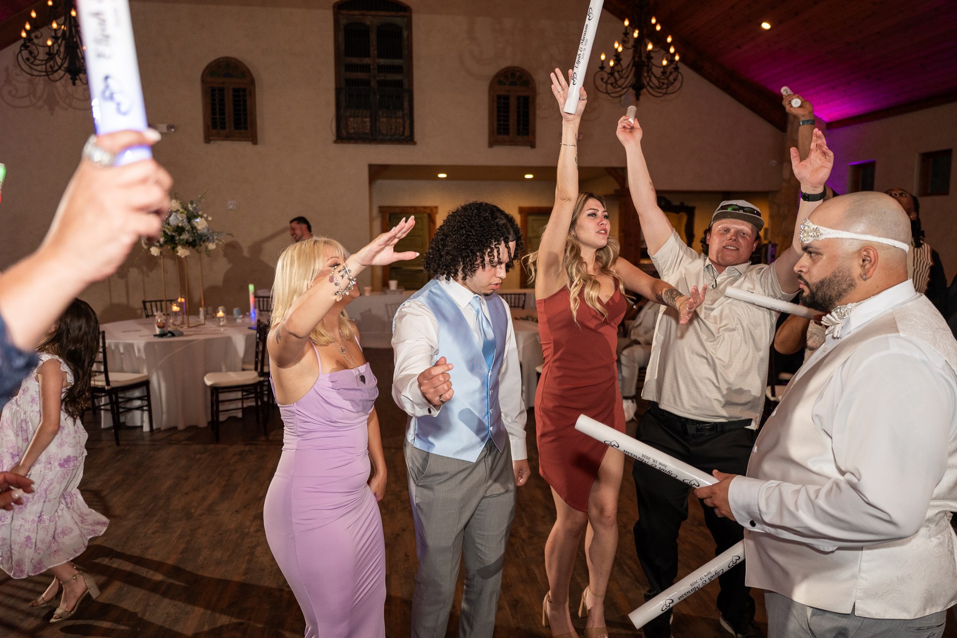 Wedding guests celebrating with light-up sticks on the dance floor