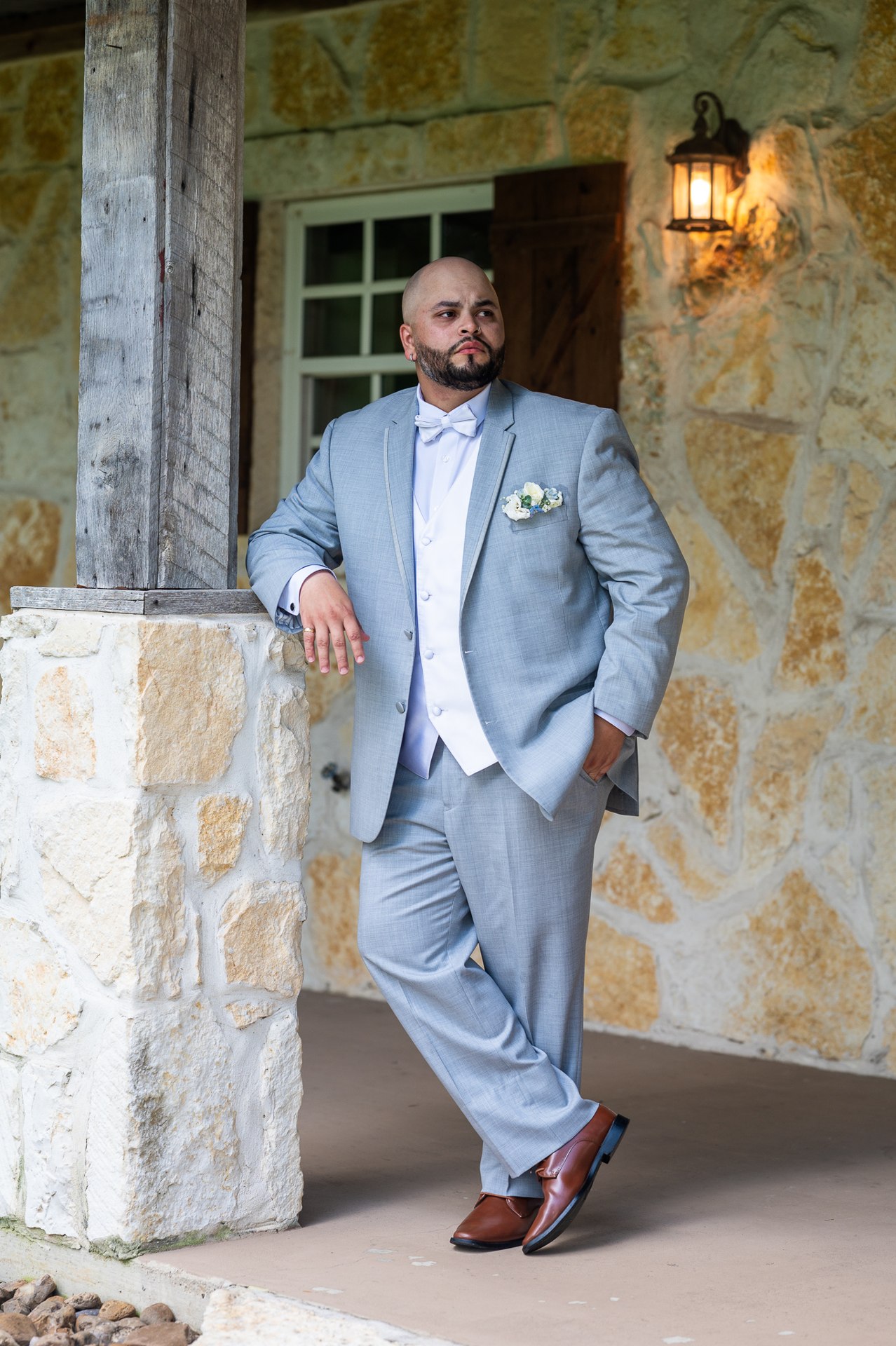 Elijah in a light gray suit beside a stone column