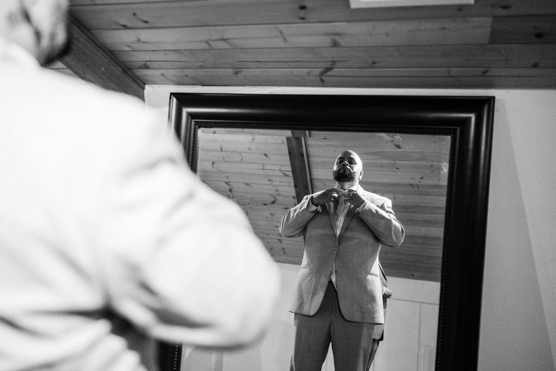 Elijah adjusting his bow tie in a mirror