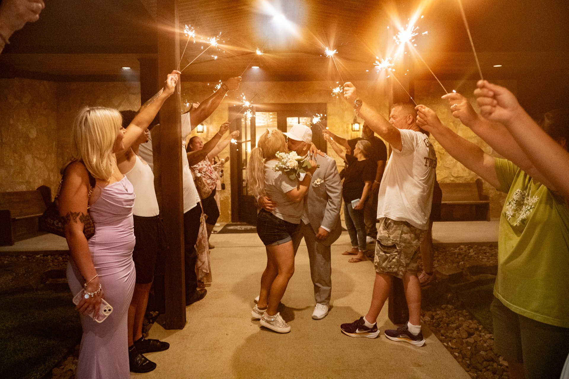 Elijah carrying Marissa between guests holding sparklers