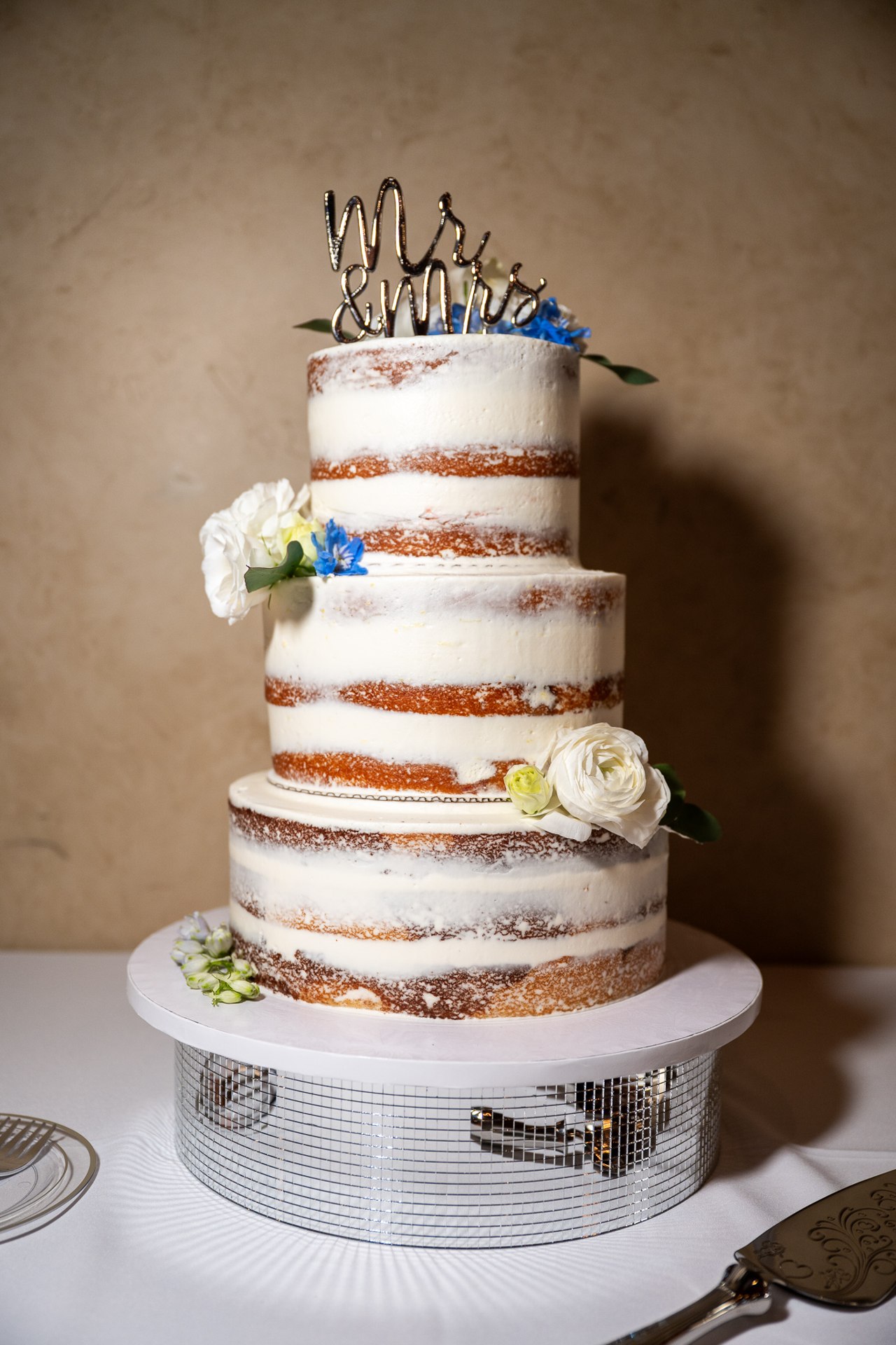 Tiered wedding cake with flowers and a Mr and Mrs topper