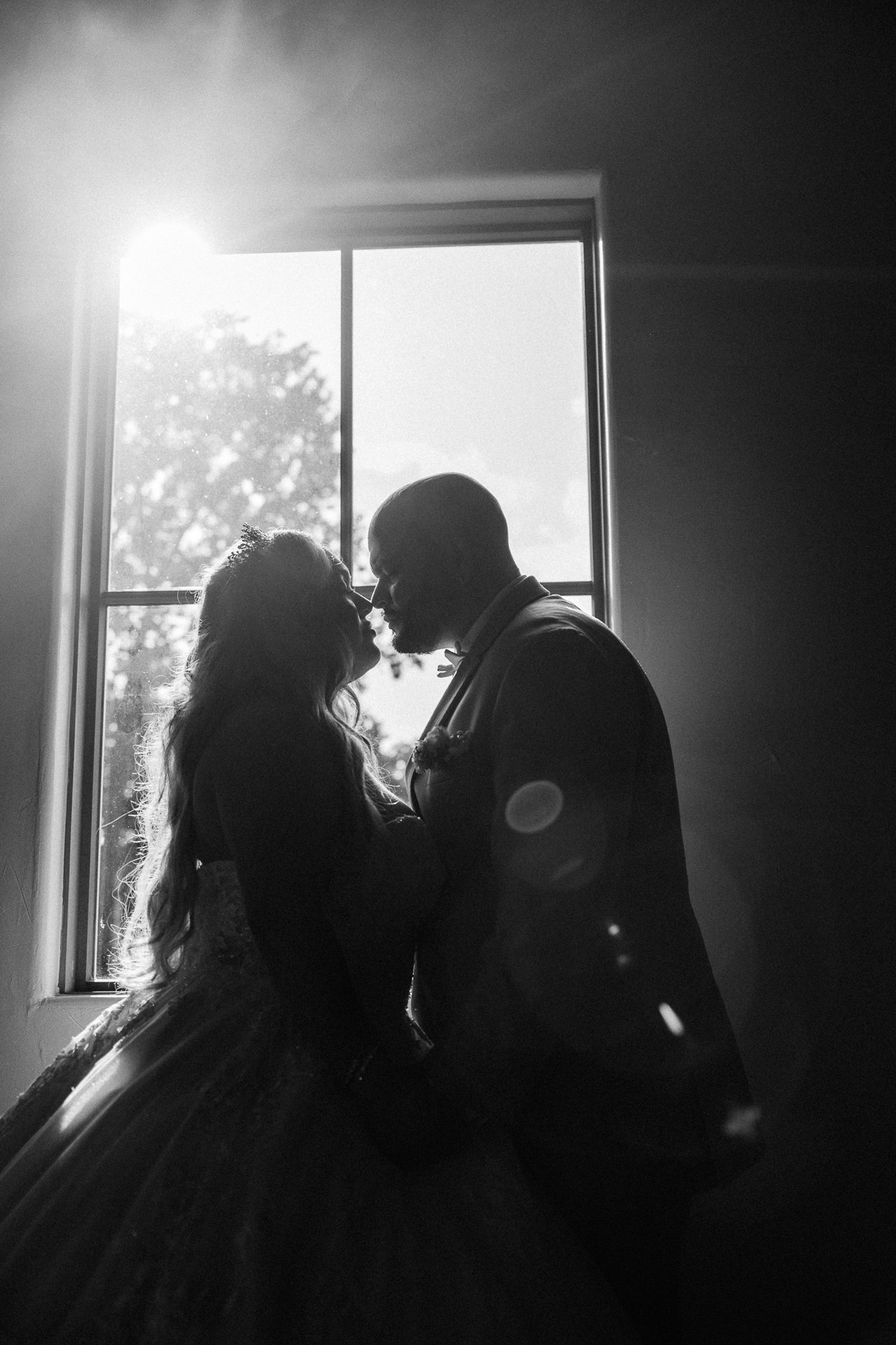 Elijah and Marissa silhouetted as they kiss beside a chapel window