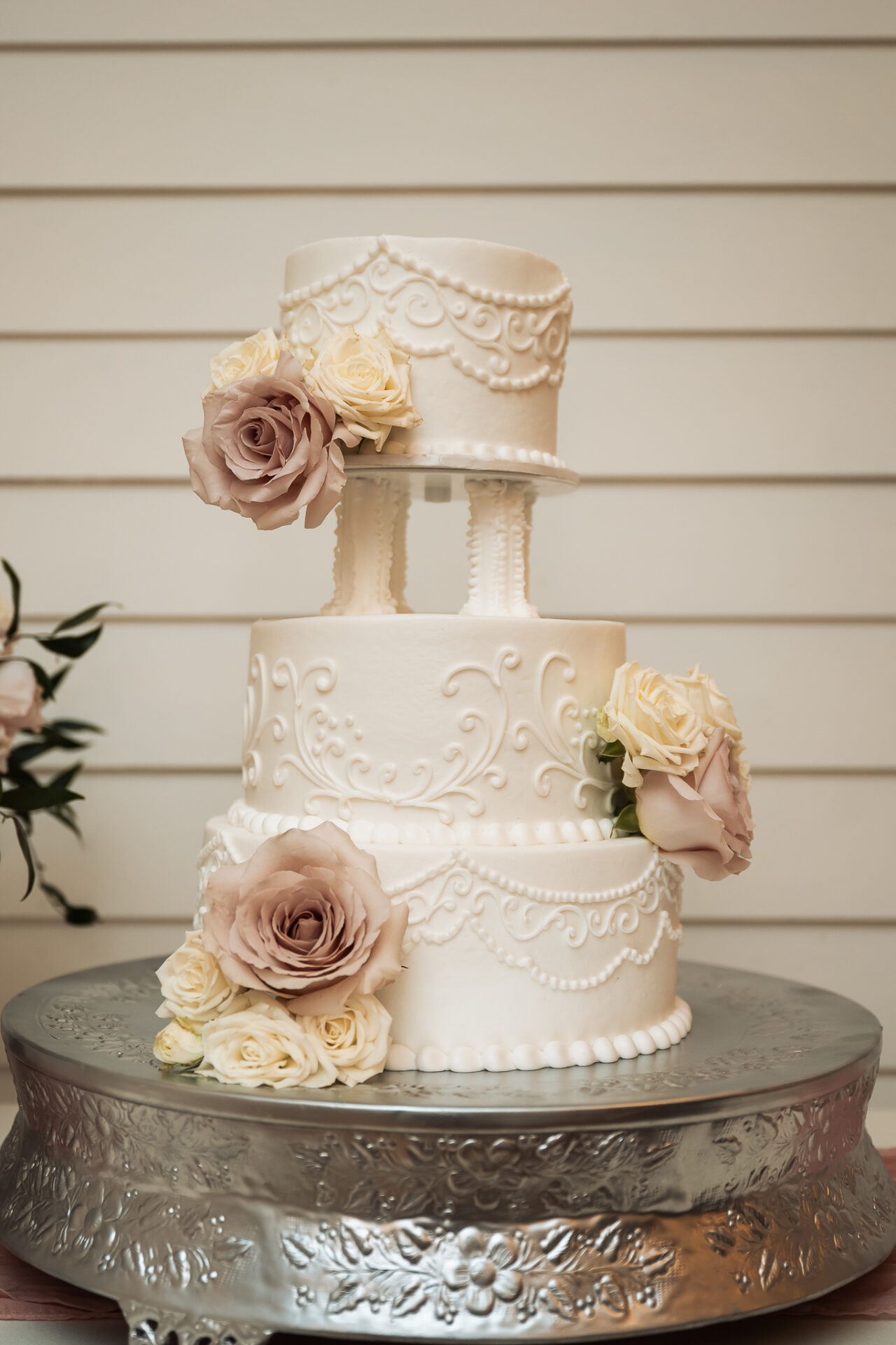 Ivory wedding cake with decorative piping and blush roses