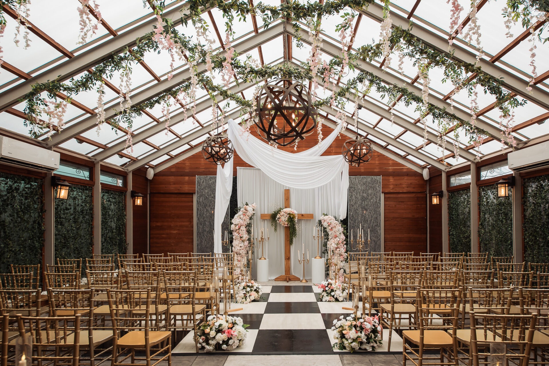 The Belamour ceremony space with gold chairs, hanging greenery, and a checkerboard aisle