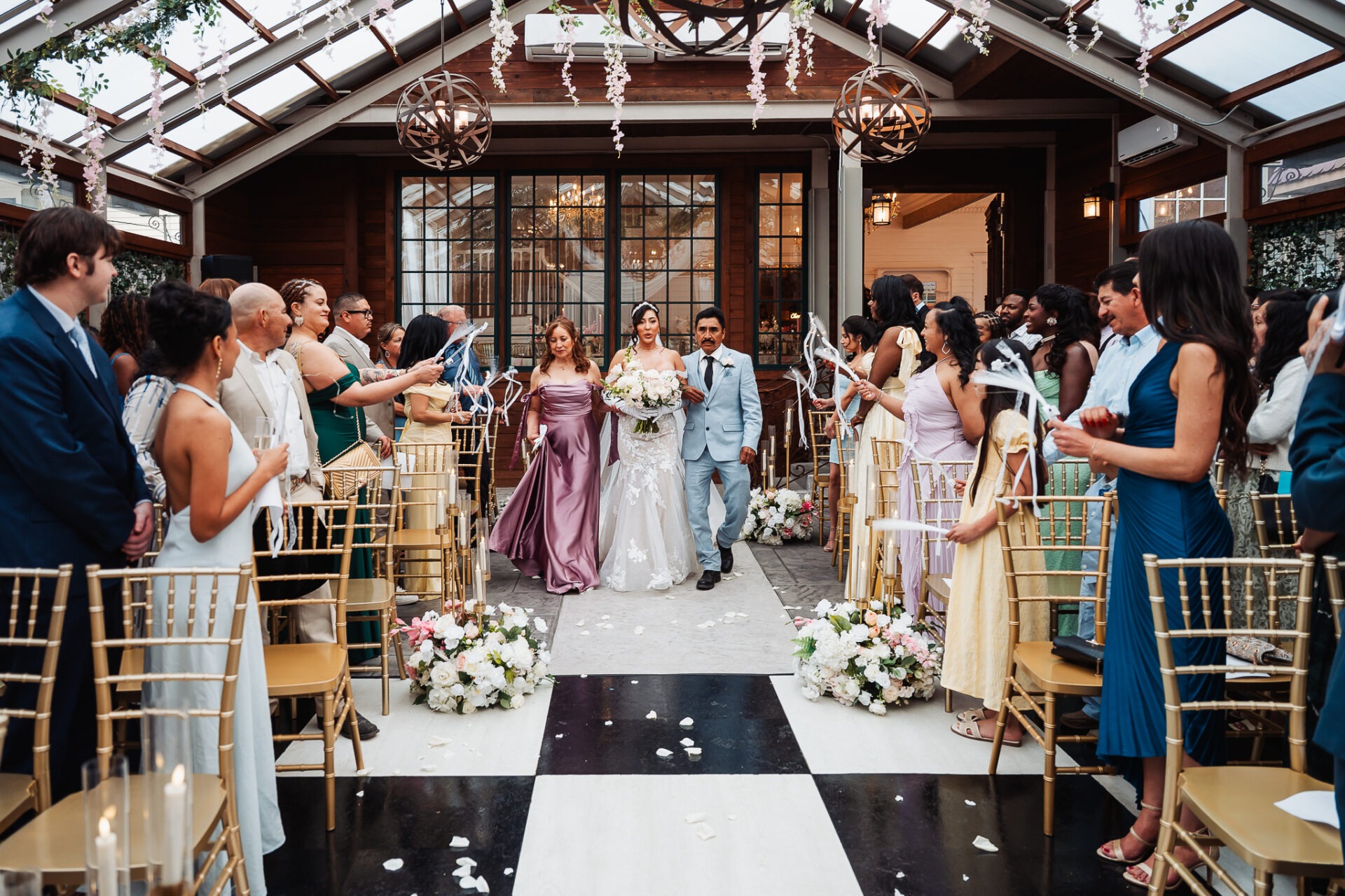 Grisel walking down the floral-lined wedding aisle with two companions