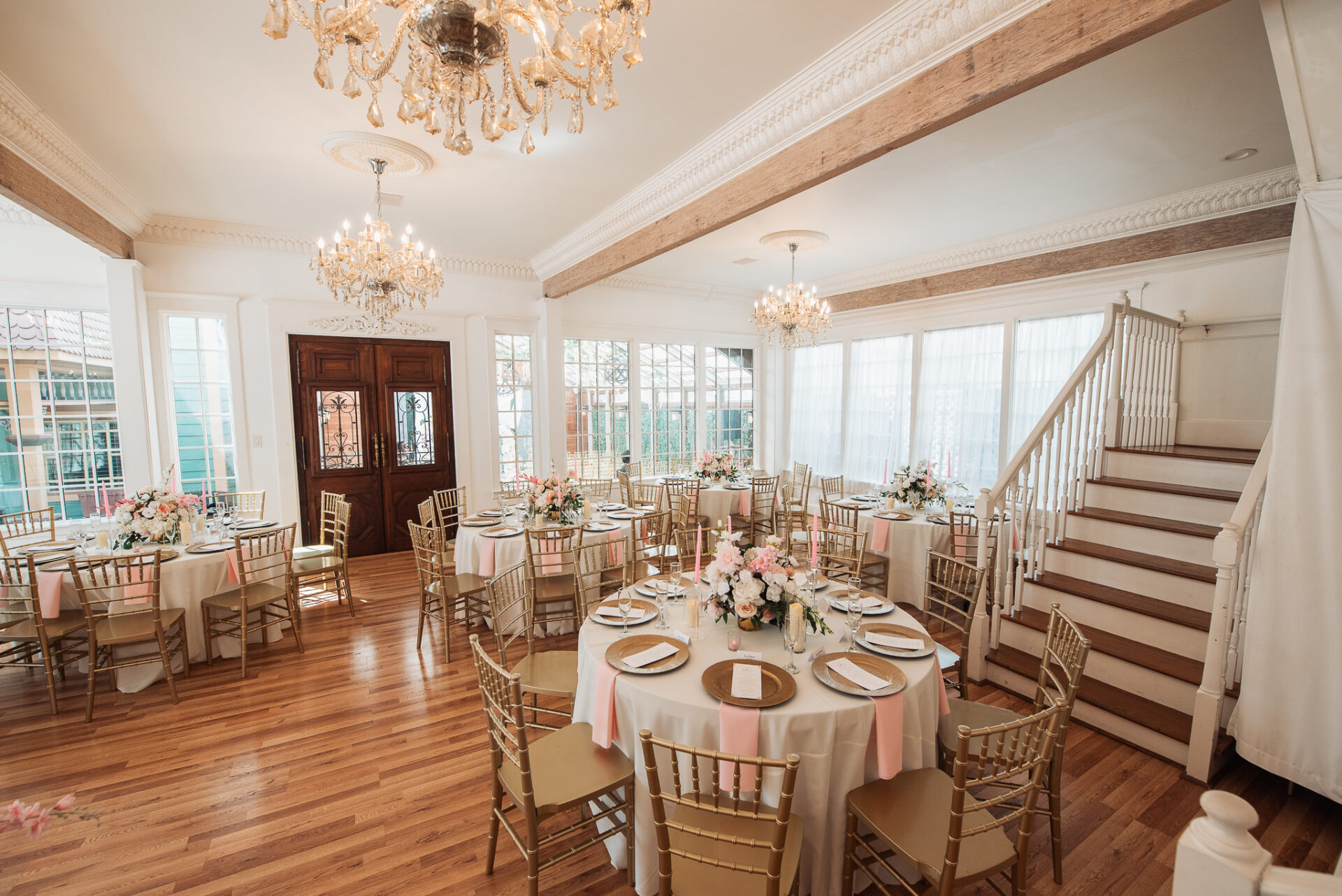 Reception tables with blush flowers, gold chairs, and crystal chandeliers