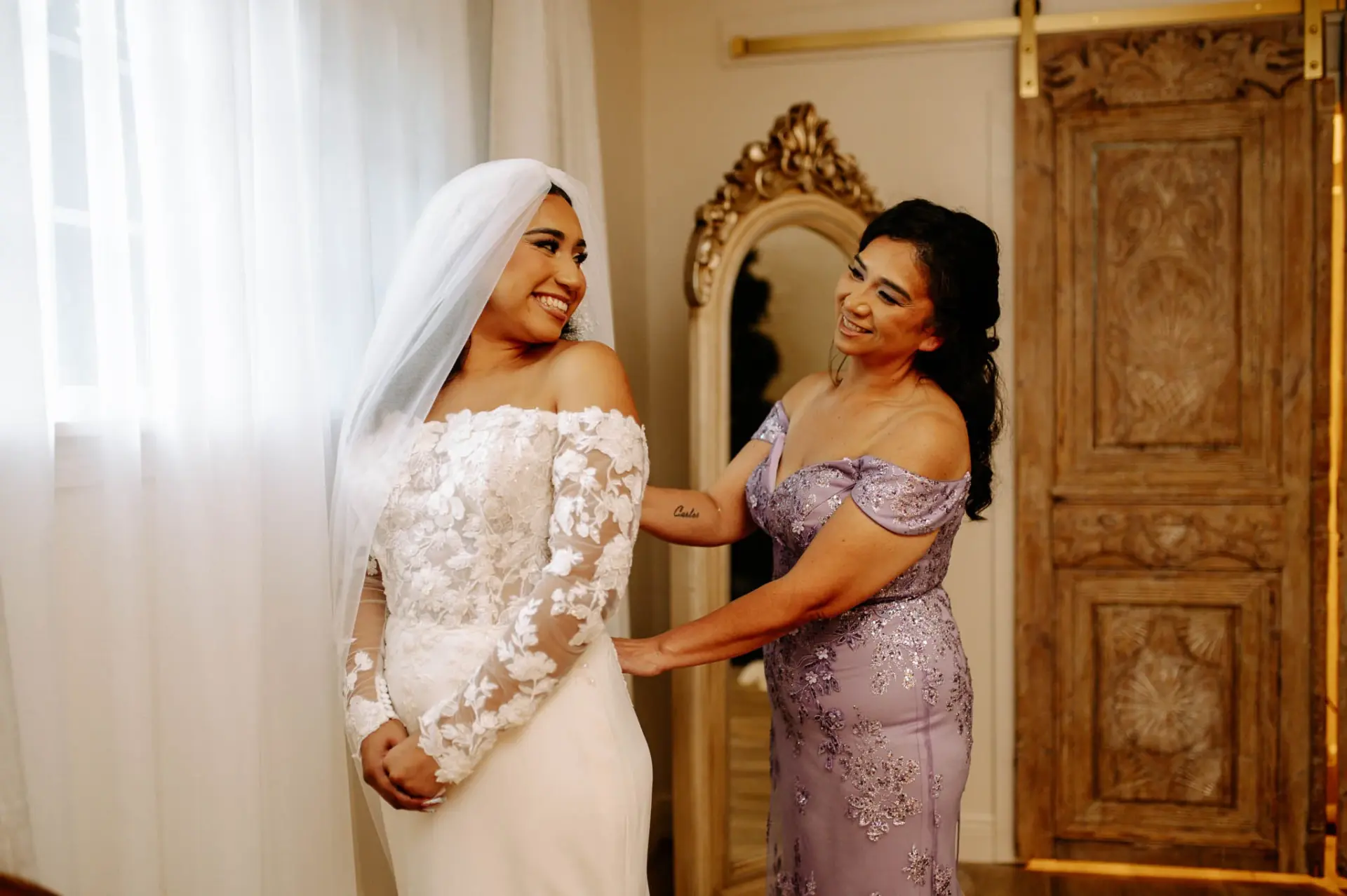 Vanessa having her wedding dress adjusted beside a window
