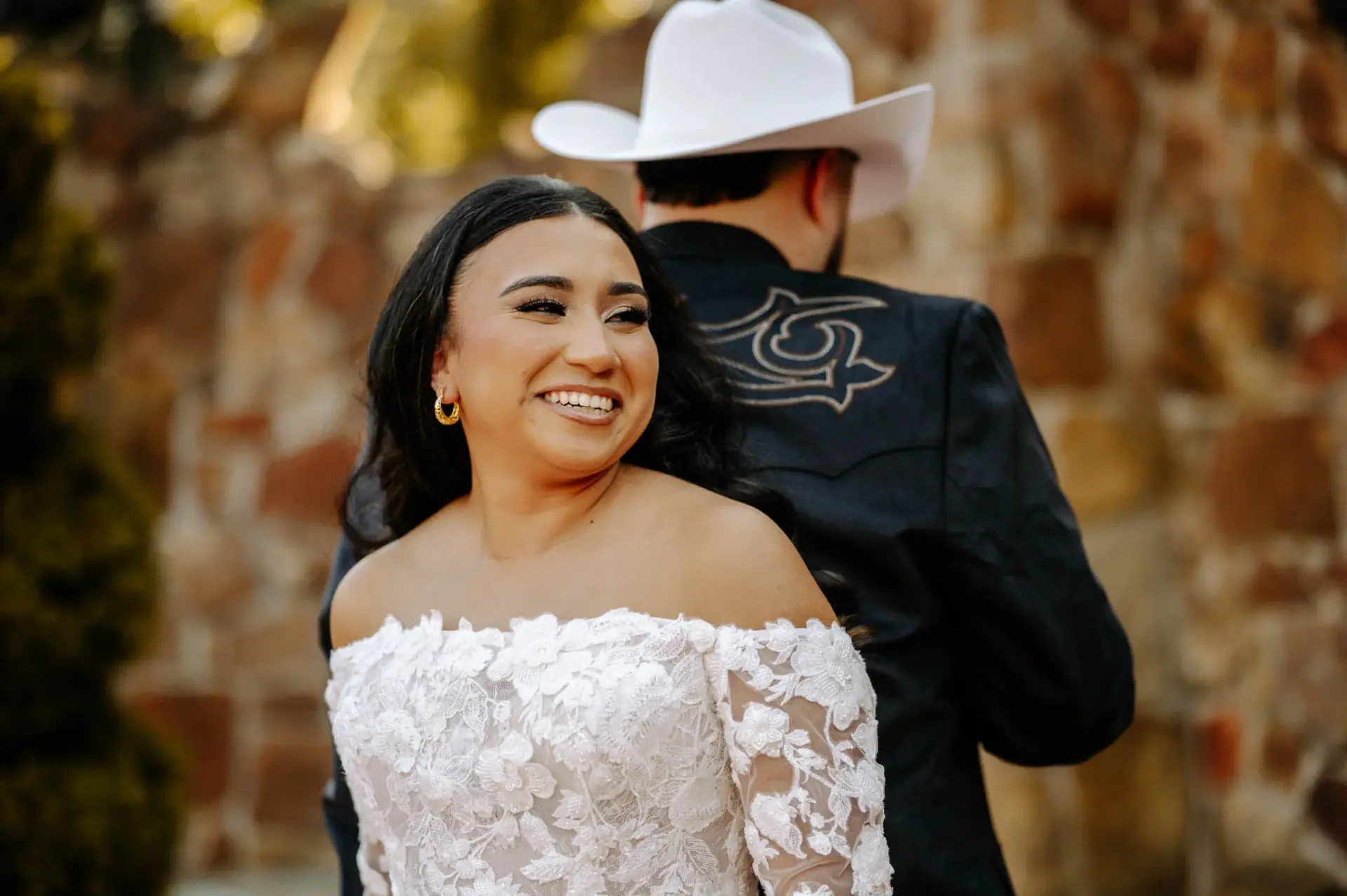 Vanessa smiling with Reymundo beside a stone wall at Madera Estates