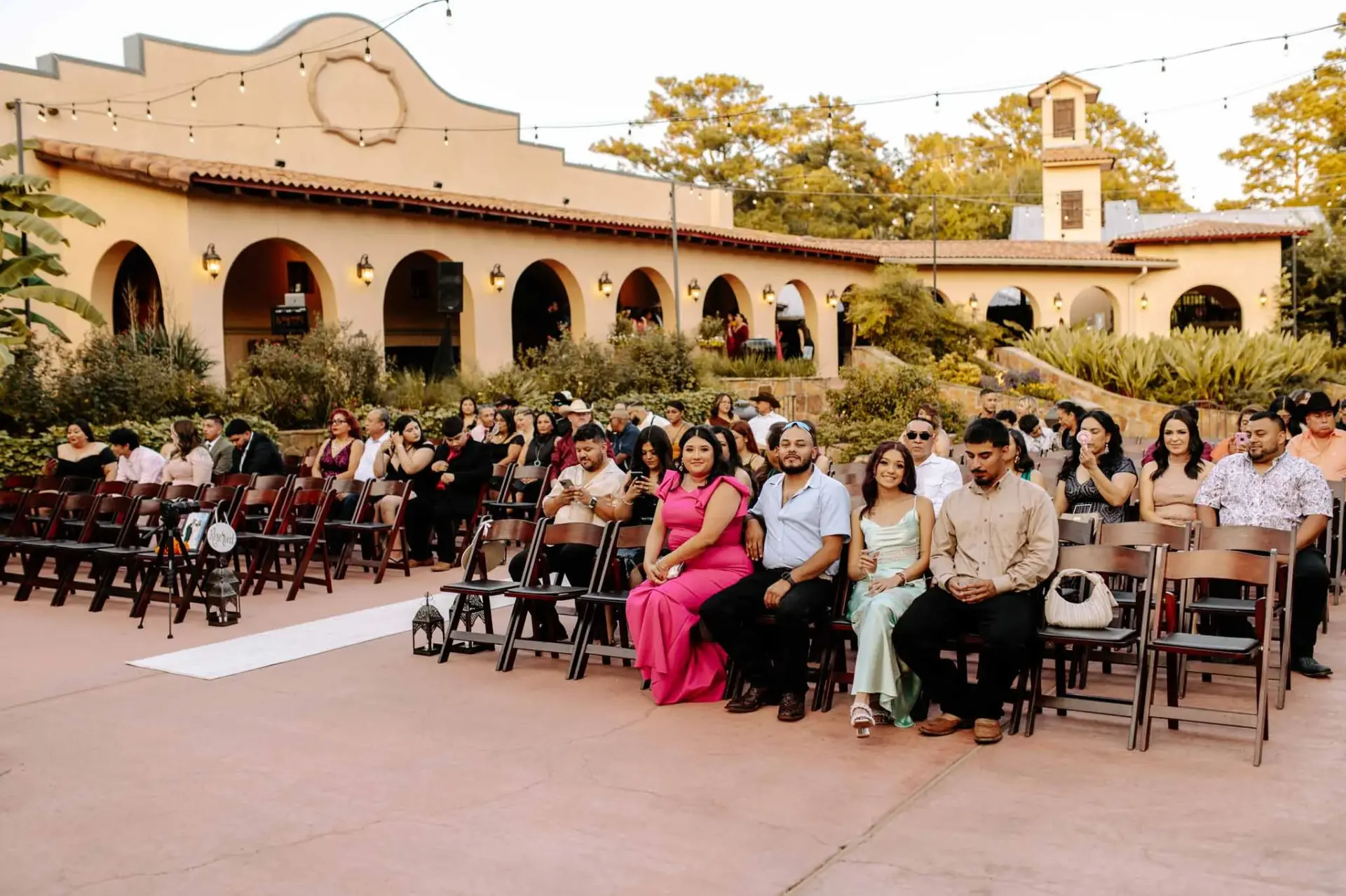 Wedding guests seated in the courtyard beneath the warm-toned venue facade