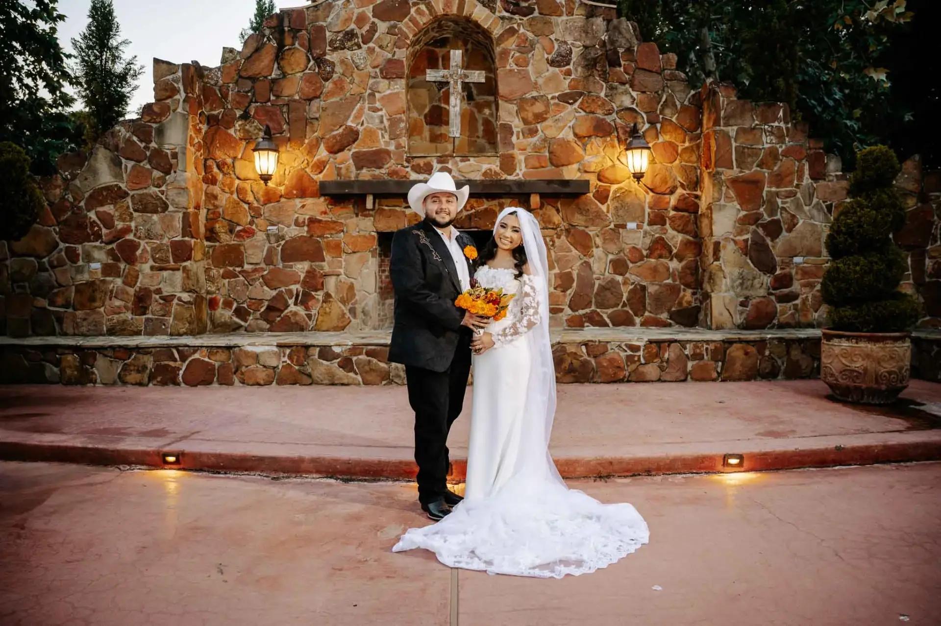 Vanessa and Reymundo posing together before the illuminated stone ceremony backdrop