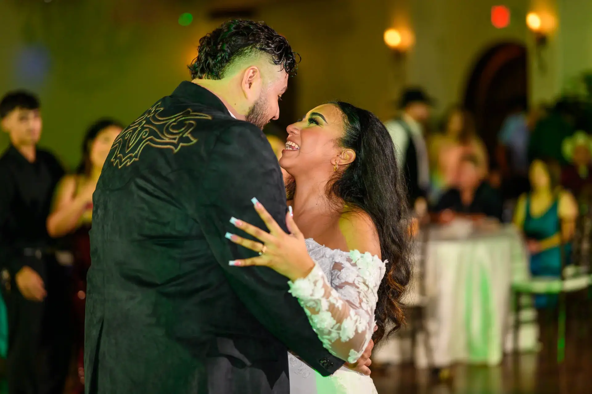 Vanessa and Reymundo embracing on the colorful dance floor