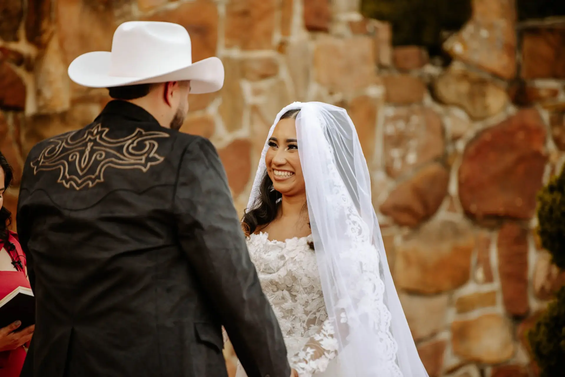 Vanessa smiling at Reymundo beside the warmly lit stone wall