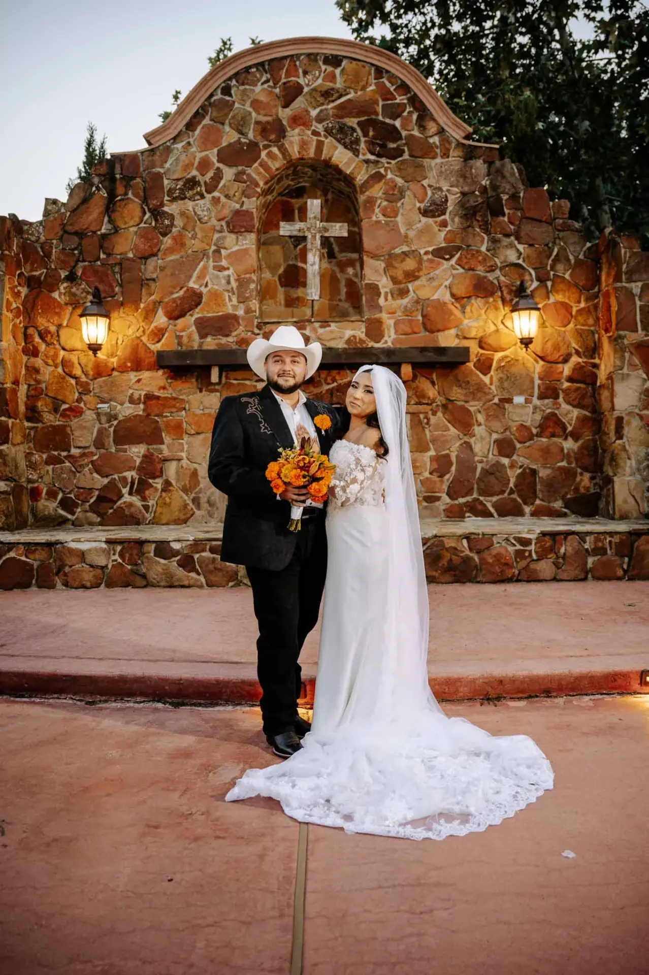Full-length portrait of Vanessa and Reymundo beside the stone fireplace