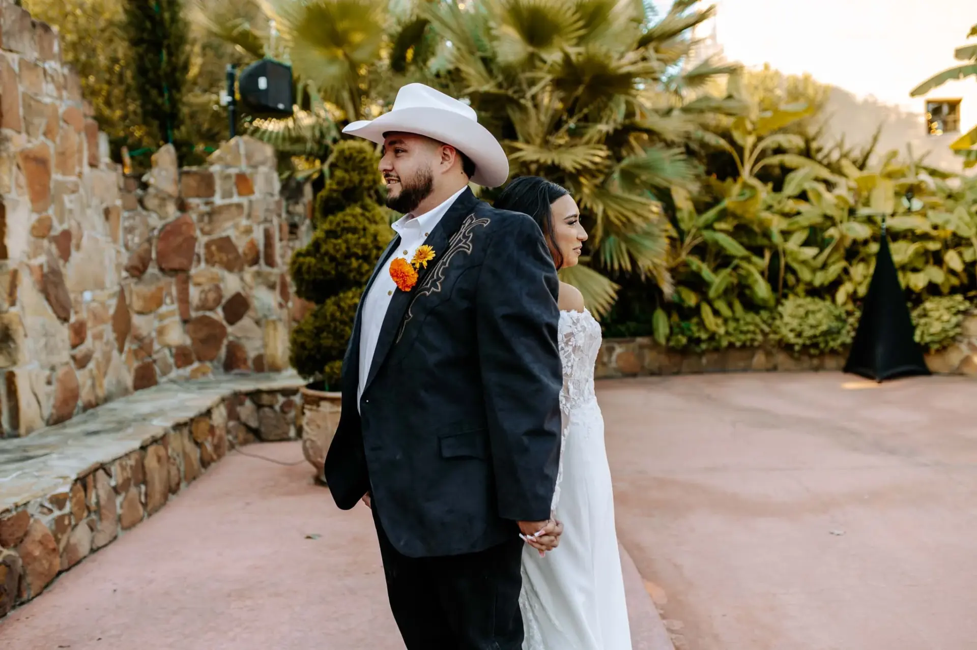 Reymundo and Vanessa standing back to back in the garden courtyard