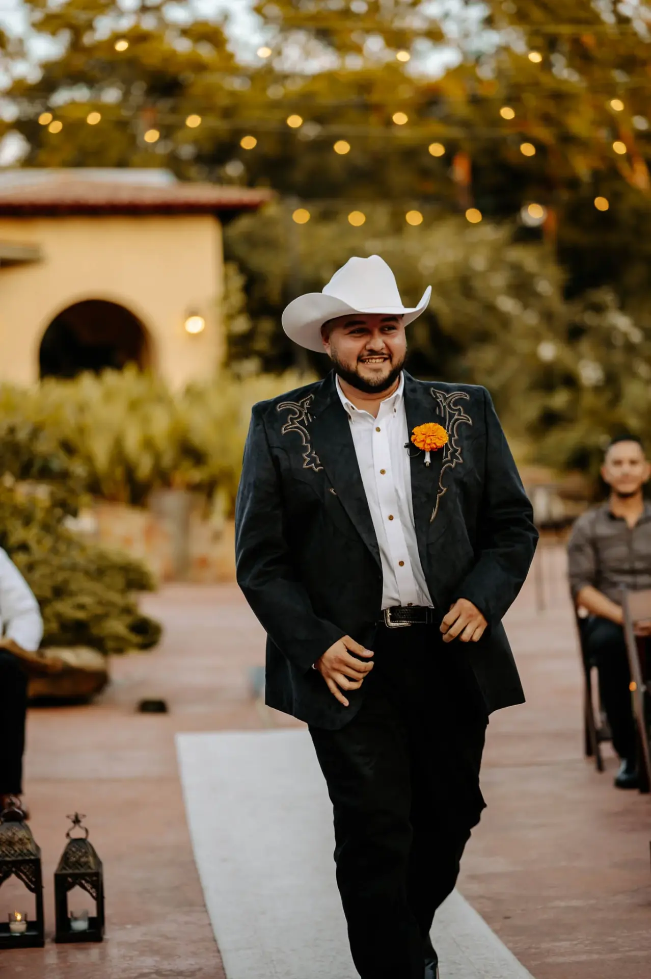 Reymundo in a black western jacket and white cowboy hat in the courtyard