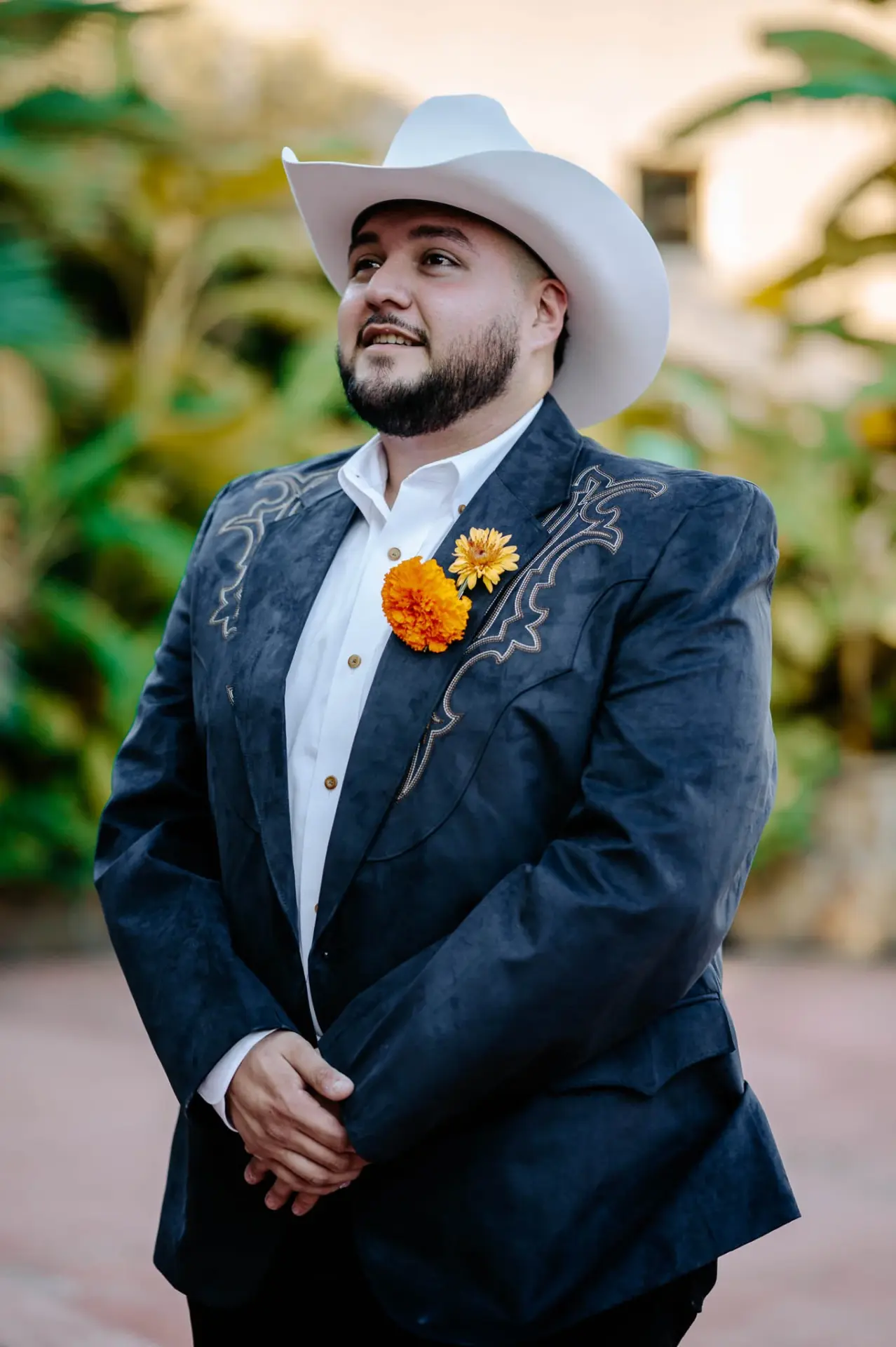 Reymundo wearing an orange boutonniere and white cowboy hat outdoors