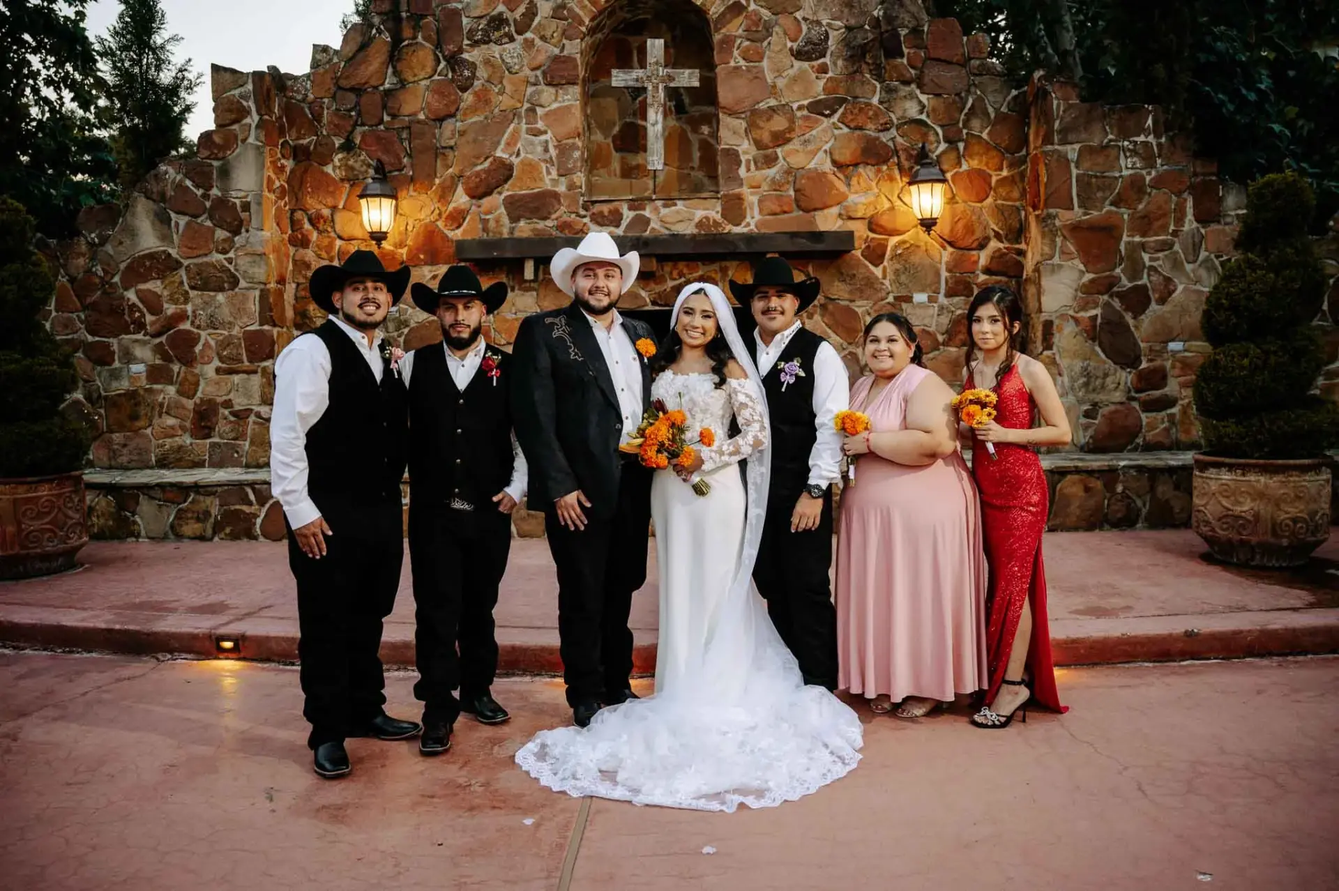 Vanessa and Reymundo with their wedding party in front of the stone backdrop