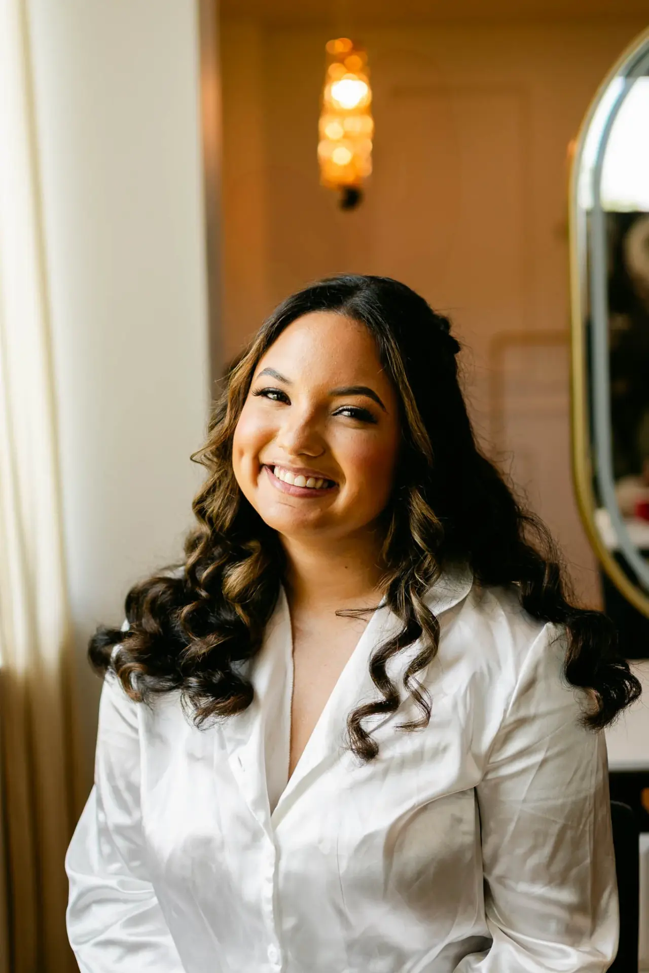 Lauren smiling in her wedding dress beside a softly lit window