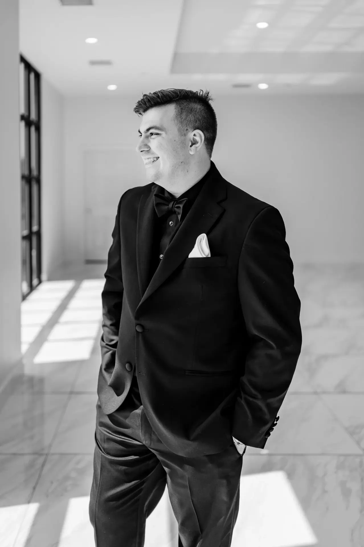 Kyle in a black tuxedo beside a bright window