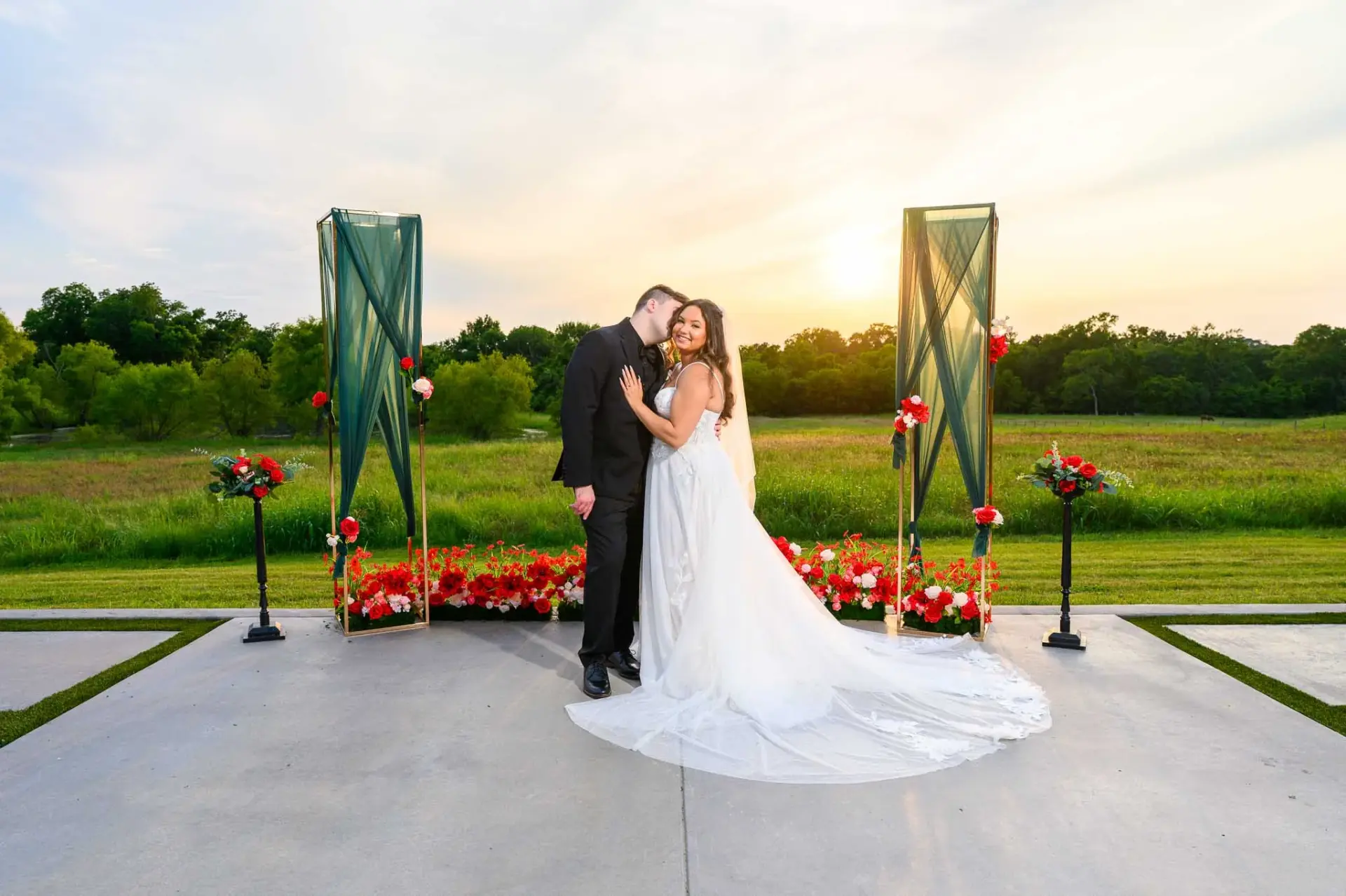 Kyle and Lauren beneath a floral ceremony installation at sunset