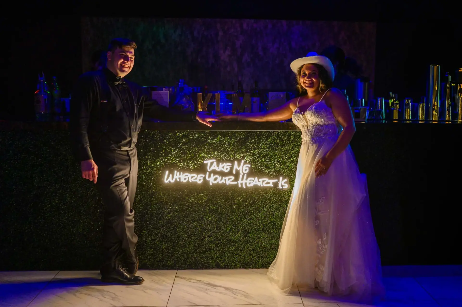 Kyle and Lauren posing beside a glowing marquee sign at night