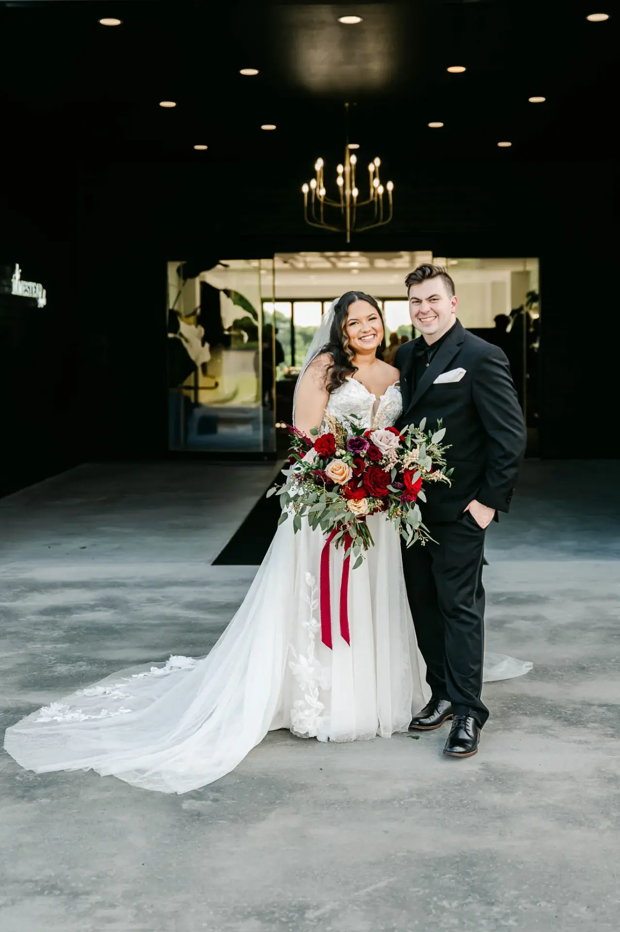 Kyle and Lauren together beneath the reception chandelier