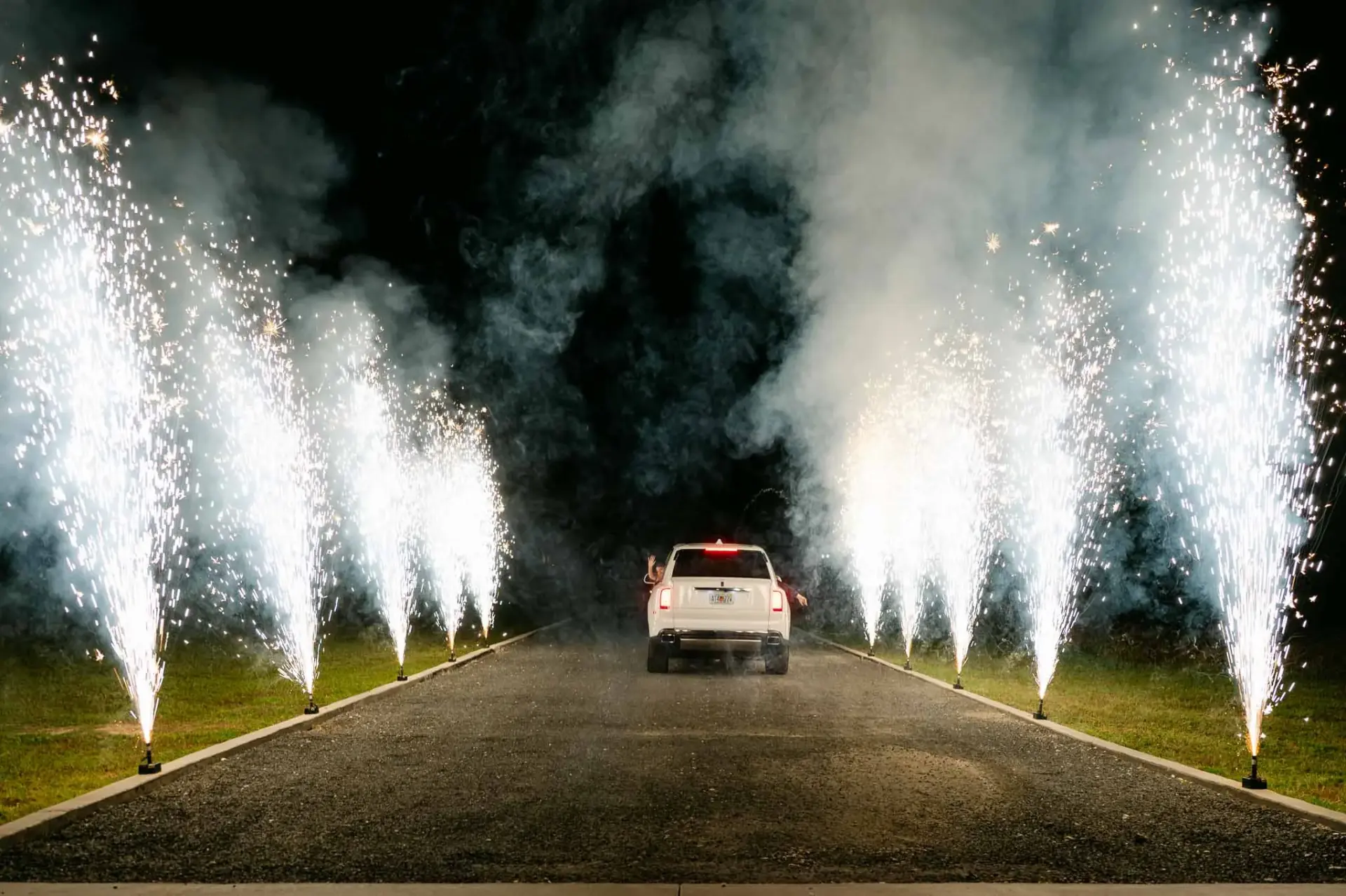 A getaway car driving between rows of wedding sparklers